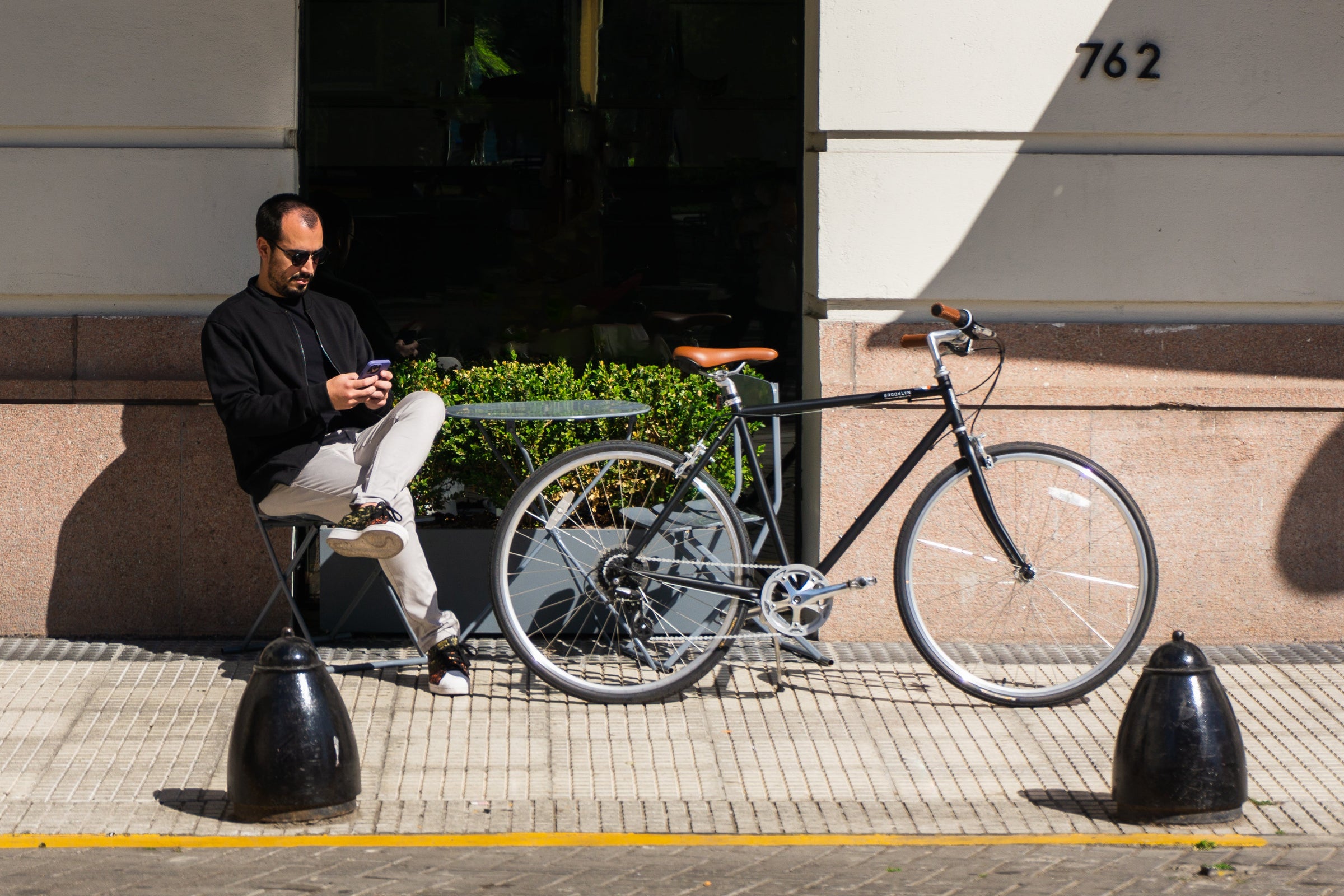 Black Bedford bike with man sitting to the left on his phone